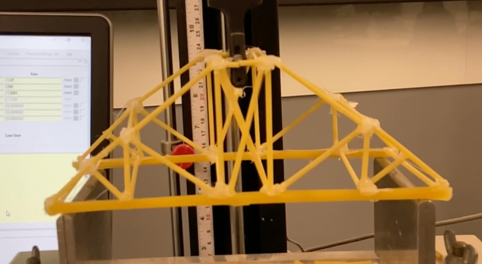 The team's final pasta truss bridge in the load-testing machine